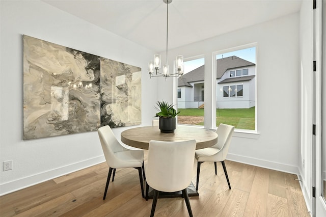 dining space with hardwood / wood-style flooring, plenty of natural light, and an inviting chandelier