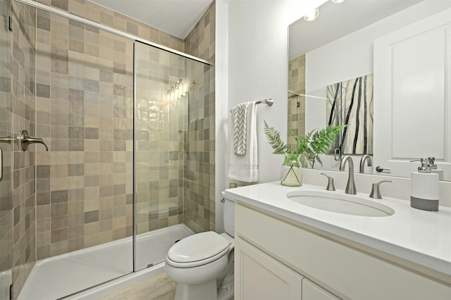 bathroom featuring toilet, a shower with door, and vanity