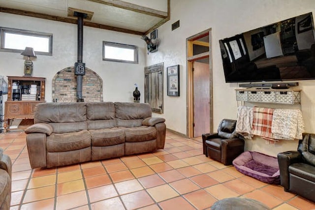 living room with a high ceiling, a wood stove, and tile floors