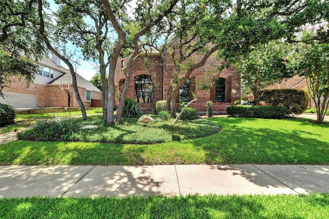 tudor home featuring a garage and a front lawn