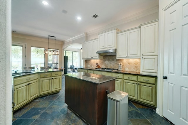 kitchen featuring pendant lighting, decorative backsplash, a kitchen island, kitchen peninsula, and stainless steel gas cooktop