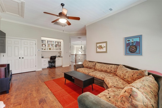 living room featuring built in shelves, ceiling fan, dark wood-type flooring, crown molding, and built in desk