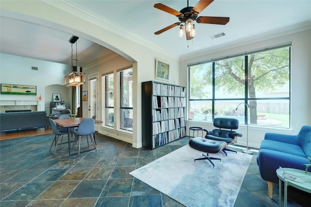 living room with a wealth of natural light, crown molding, and ceiling fan