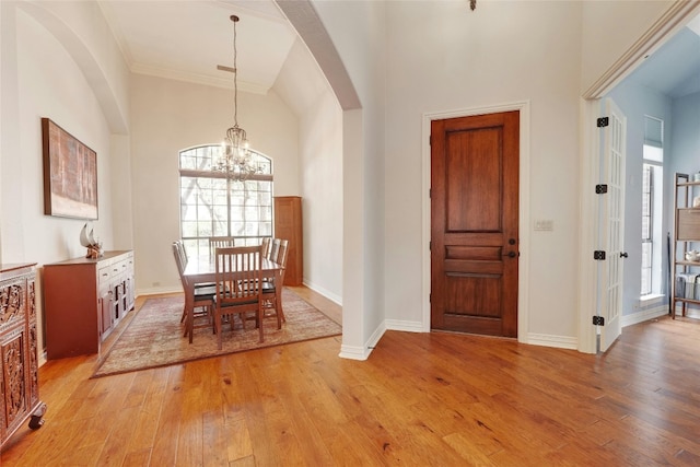 dining space with an inviting chandelier, crown molding, and light hardwood / wood-style flooring