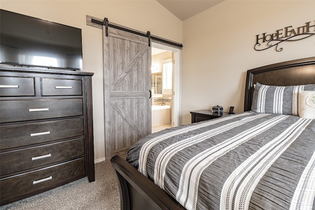 bedroom featuring a barn door, carpet, ensuite bathroom, and vaulted ceiling