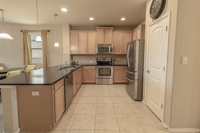 kitchen featuring kitchen peninsula, backsplash, appliances with stainless steel finishes, sink, and pendant lighting