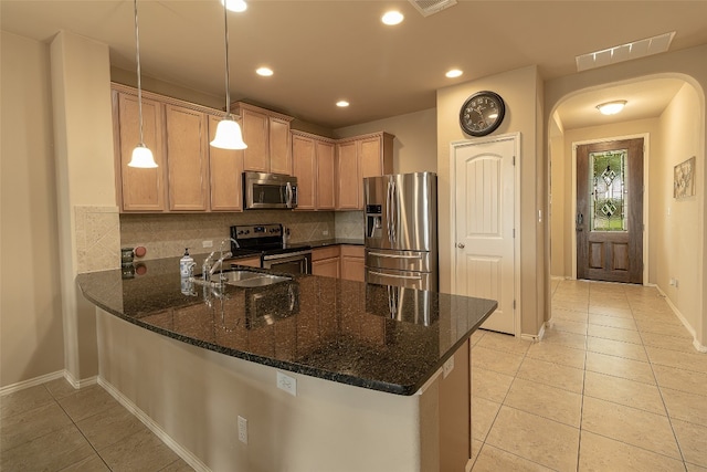 kitchen featuring stainless steel appliances, kitchen peninsula, backsplash, and pendant lighting