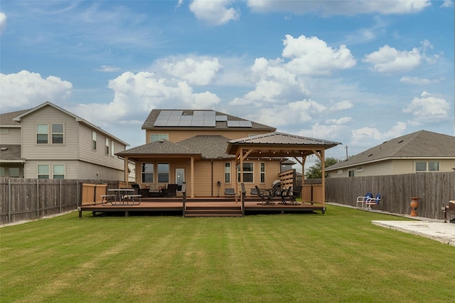 rear view of property with a deck, solar panels, and a yard