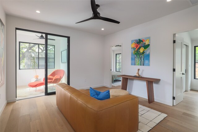 living room with plenty of natural light, ceiling fan, and light wood-type flooring