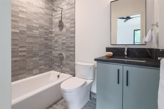 full bathroom featuring ceiling fan, tiled shower / bath combo, tile floors, toilet, and vanity