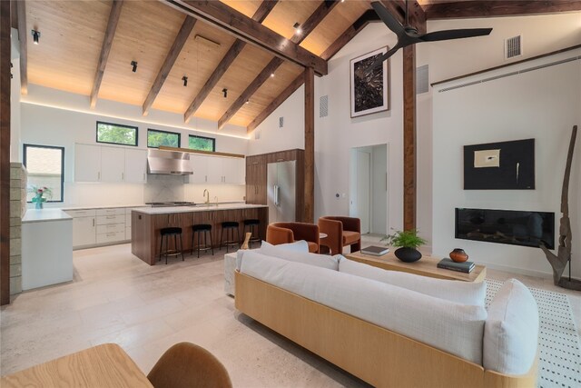 living room with ceiling fan, beamed ceiling, light tile floors, high vaulted ceiling, and wooden ceiling