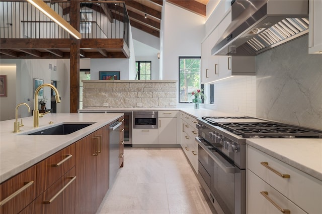 kitchen with wall chimney range hood, light tile flooring, white cabinetry, sink, and appliances with stainless steel finishes