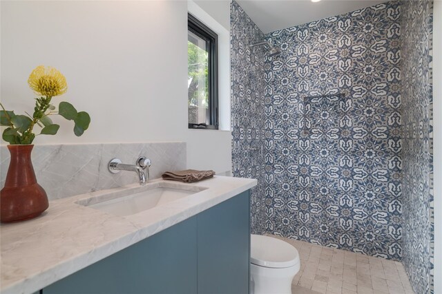 bathroom with tiled shower, vanity, and toilet