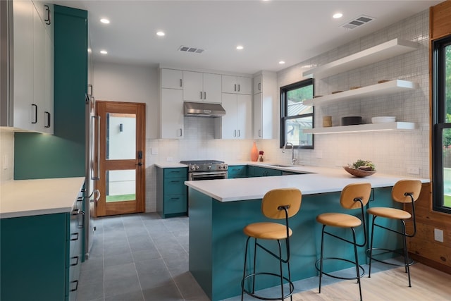 kitchen featuring tile flooring, tasteful backsplash, white cabinets, and gas range