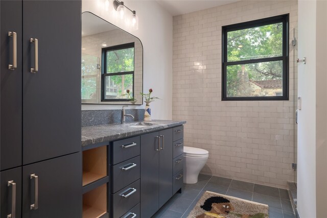 bathroom with tile walls, tile floors, plenty of natural light, and toilet