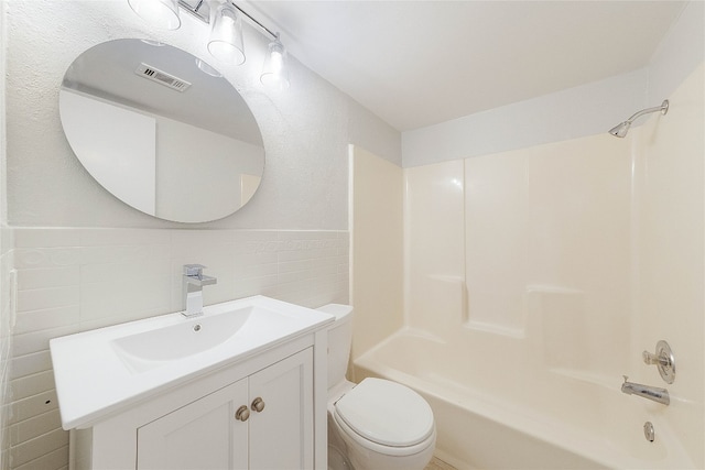 full bathroom with tile walls, toilet, large vanity, and bathing tub / shower combination