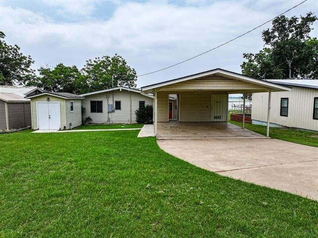 view of front facade with a front yard, a shed, and a carport