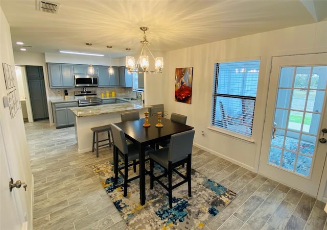 dining room featuring light wood-type flooring, a notable chandelier, and sink