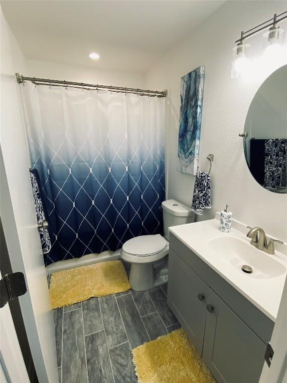 bathroom with a shower with shower curtain, vanity, and toilet