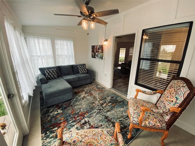 tiled living room with ceiling fan and lofted ceiling