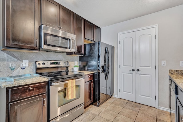 kitchen featuring light stone countertops, dark brown cabinets, light tile patterned flooring, and stainless steel appliances