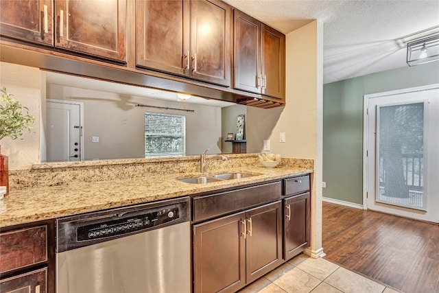 kitchen featuring dishwasher, light stone countertops, sink, and light tile patterned floors