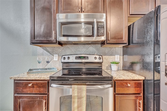 kitchen featuring stainless steel appliances, light stone counters, and tasteful backsplash