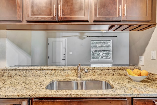 kitchen with light stone countertops, dishwasher, and sink