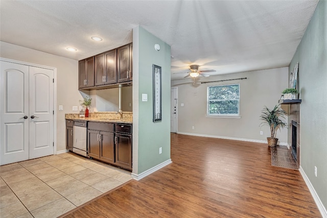 kitchen featuring stainless steel dishwasher, a textured ceiling, dark brown cabinetry, ceiling fan, and light hardwood / wood-style floors