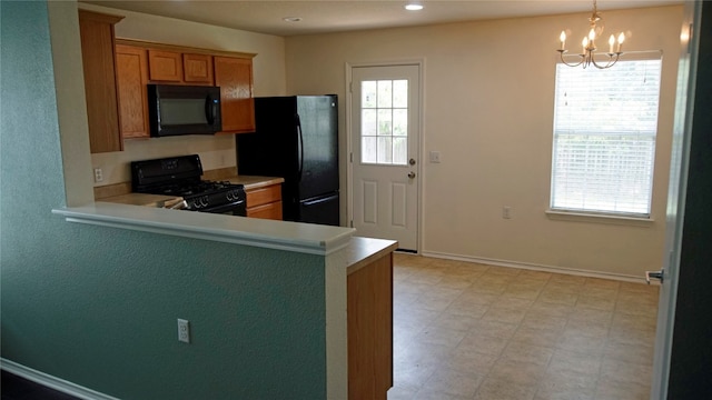 kitchen with black appliances, an inviting chandelier, light tile floors, and pendant lighting