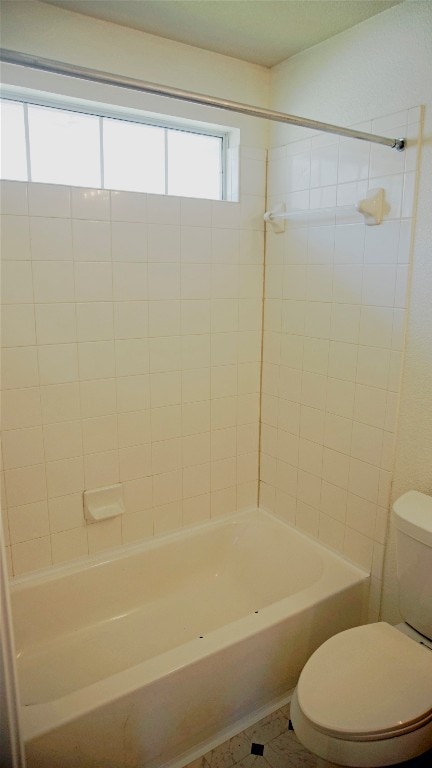 bathroom with tiled shower / bath, tile flooring, and toilet