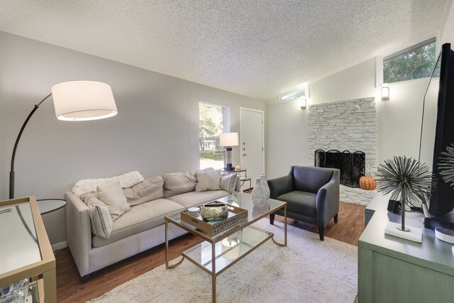 living room with a fireplace, lofted ceiling, a textured ceiling, and hardwood / wood-style floors