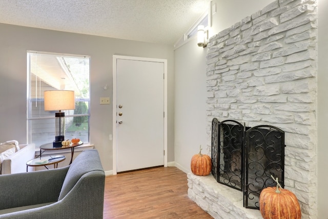 living room featuring a textured ceiling, light wood-type flooring, and a fireplace