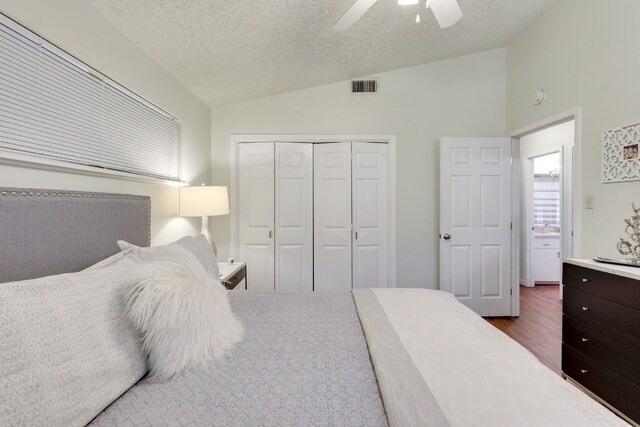 bedroom with vaulted ceiling, dark hardwood / wood-style flooring, a closet, ceiling fan, and a textured ceiling