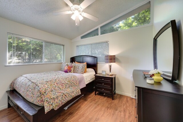 bedroom featuring vaulted ceiling, ceiling fan, light hardwood / wood-style floors, and a textured ceiling