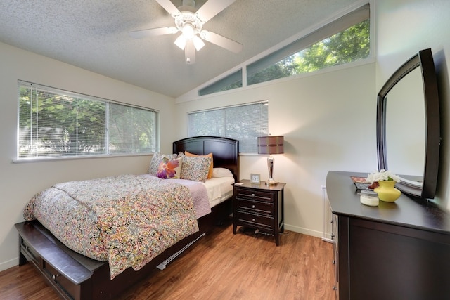 bedroom featuring ceiling fan, lofted ceiling, a textured ceiling, and light wood-type flooring