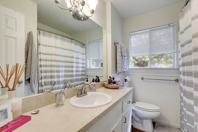 bathroom with a notable chandelier, a textured ceiling, toilet, and vanity with extensive cabinet space