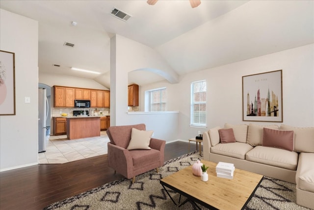 living room featuring ceiling fan, lofted ceiling, and light wood-type flooring