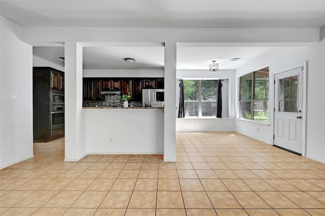 kitchen featuring dark brown cabinetry, light tile flooring, tasteful backsplash, and appliances with stainless steel finishes