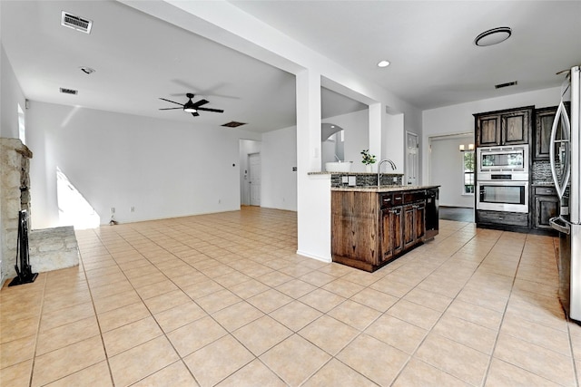 kitchen featuring appliances with stainless steel finishes, light tile flooring, ceiling fan, and dark brown cabinetry