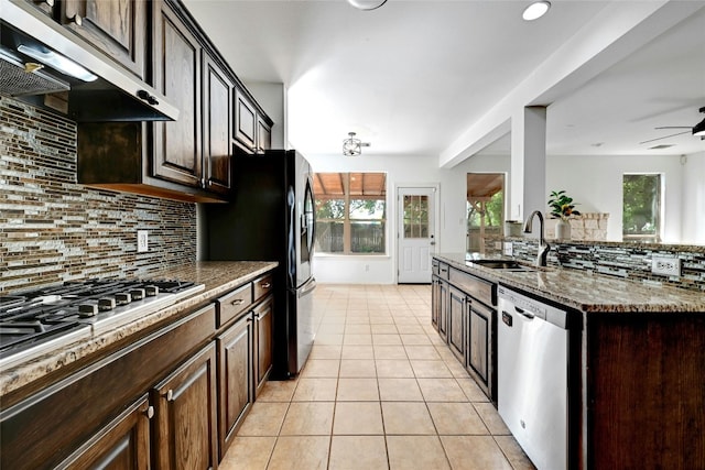 kitchen featuring stainless steel appliances, backsplash, sink, ceiling fan, and light tile floors