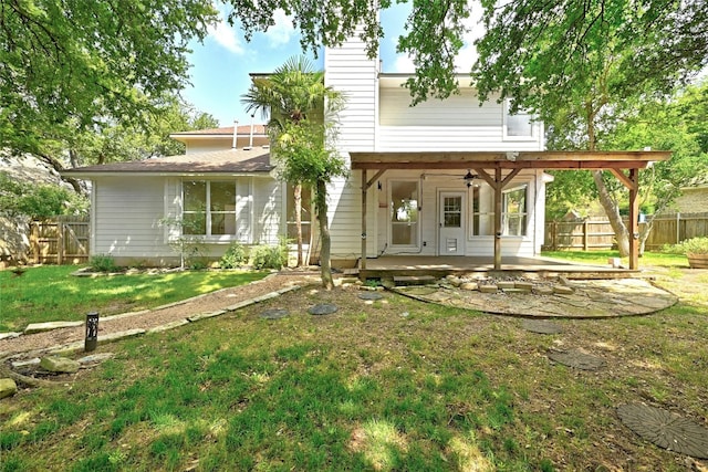 rear view of house featuring ceiling fan and a lawn