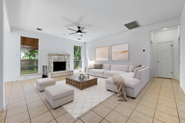 living room with a wealth of natural light, a fireplace, ceiling fan, and light tile floors