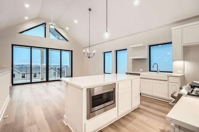 kitchen with appliances with stainless steel finishes, decorative light fixtures, sink, white cabinets, and a center island