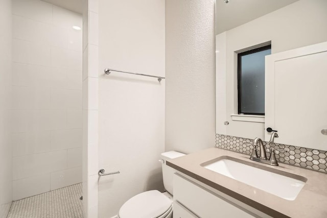 bathroom with vanity, tiled shower, and toilet