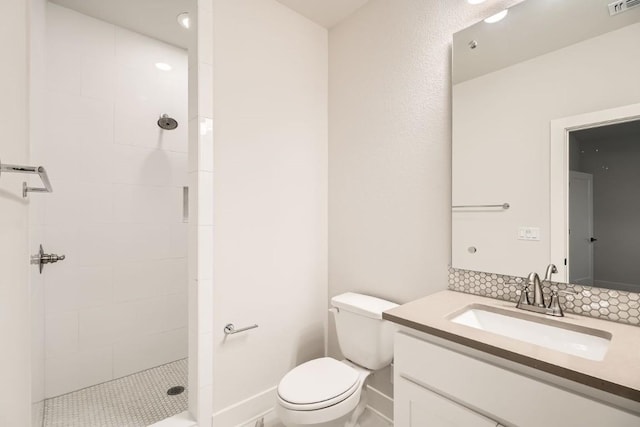 bathroom with vanity, toilet, and a tile shower