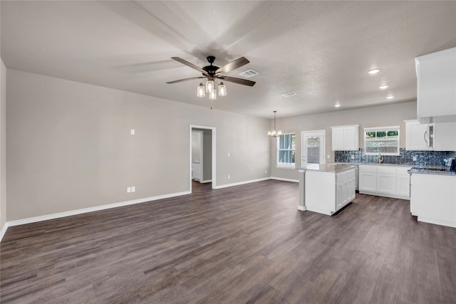 kitchen with ceiling fan with notable chandelier, dark hardwood / wood-style floors, white cabinets, and decorative light fixtures