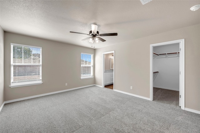 unfurnished bedroom with ceiling fan, a closet, ensuite bath, and a spacious closet