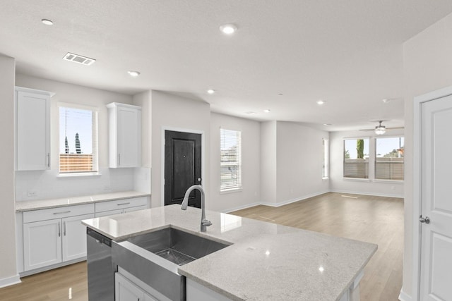 kitchen featuring light stone countertops, sink, dishwasher, white cabinetry, and light hardwood / wood-style floors