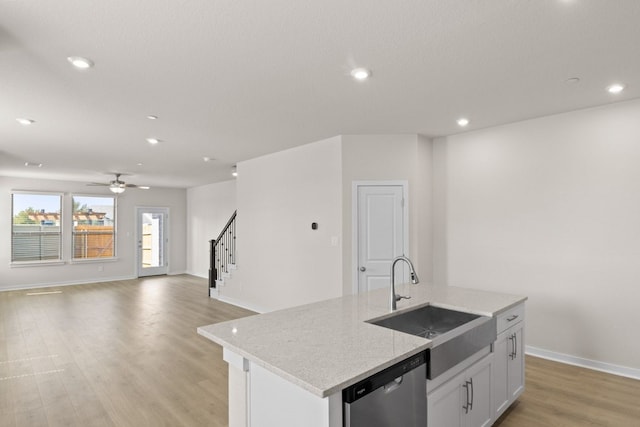 kitchen featuring light hardwood / wood-style flooring, a center island with sink, sink, stainless steel dishwasher, and white cabinets